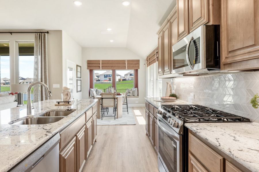 Kitchen with brown wood cabinets, granite countertops, stainless steel appliances, and chevron tile backsplash