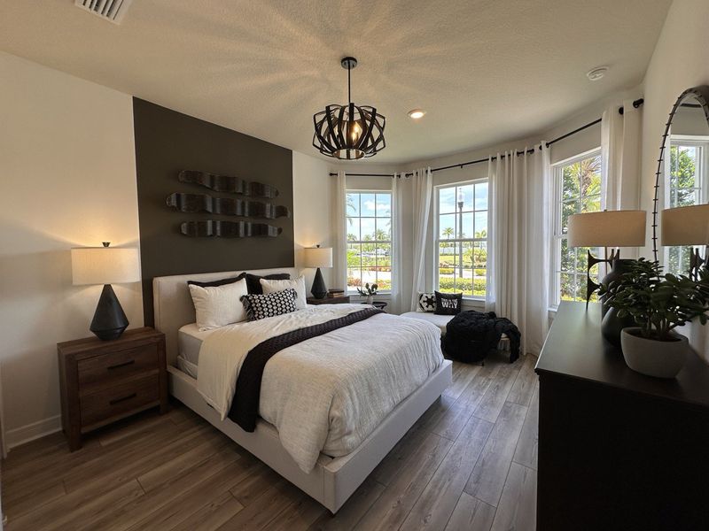 A chic bedroom featuring a statement wall, elegant lighting, and large windows with a serene view, exuding modern comfort.