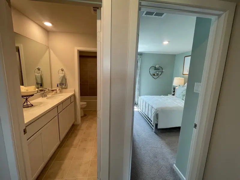 A cozy bathroom with a dual vanity and a well-decorated bedroom featuring soft hues and a heart-shaped shelf.