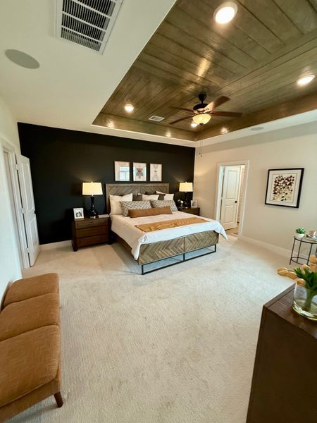 Spacious bedroom with a modern dark accent wall, wooden ceiling, cozy lighting, and elegant decor.