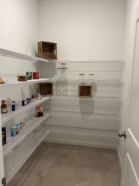 A spacious pantry with white wire shelving and tiled flooring, perfect for organized kitchen storage.
