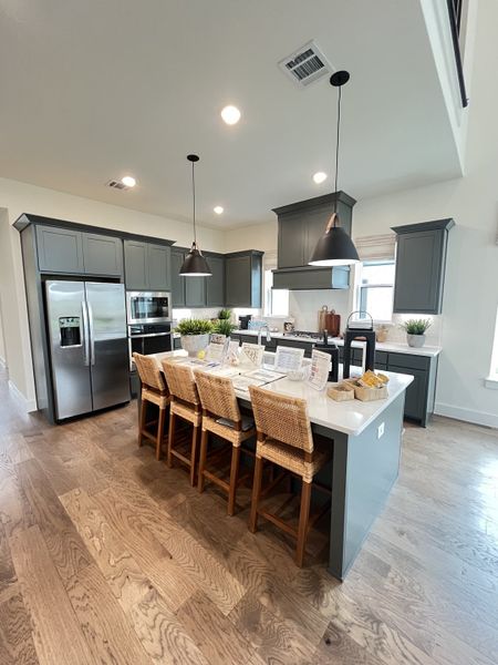 A modern kitchen with elegant gray cabinetry, hardwood floors, and a central island with woven bar stools. A modern kitchen with elegant gray cabinetry, hardwood floors, and a central island with woven bar stools.