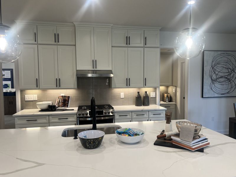 A modern kitchen with sleek white cabinetry, a large marble island, and elegant pendant lighting.