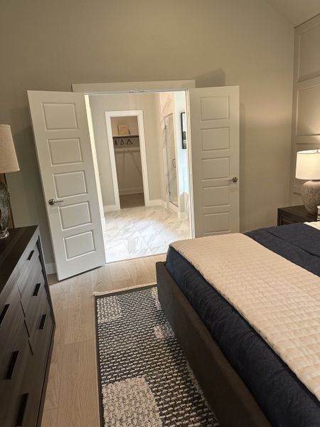 Elegant bedroom featuring a cozy bed, soft lighting, and stylish double doors leading to a chic, tiled walk-in closet.