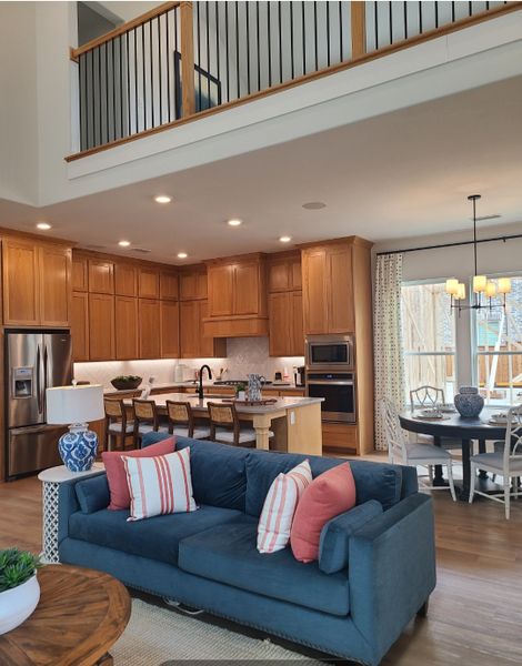 A modern open-concept living area with a cozy blue sofa, warm wood kitchen, and dining space, featuring elegant decor.