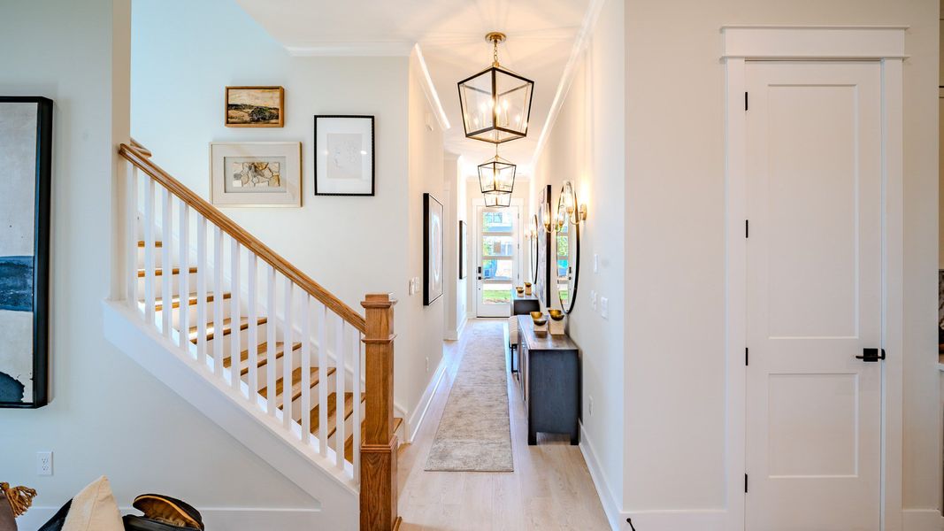 Entryway facing the front door with pendant lighting and access to staircase