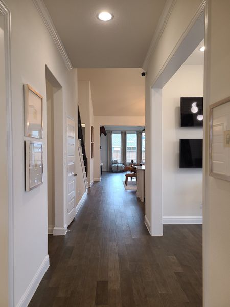 A bright hallway with elegant wood flooring, modern decor, and inviting natural light leading to a spacious living area.