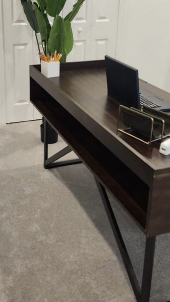 A sleek home office with a dark wood desk, open shelving, and lush greenery, creating a productive and inviting workspace.