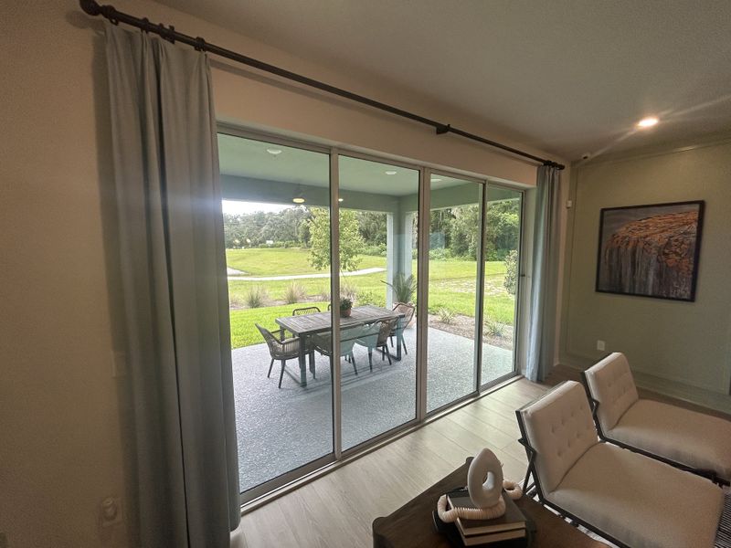 A cozy living area with large glass doors leading to a covered patio and serene outdoor view.