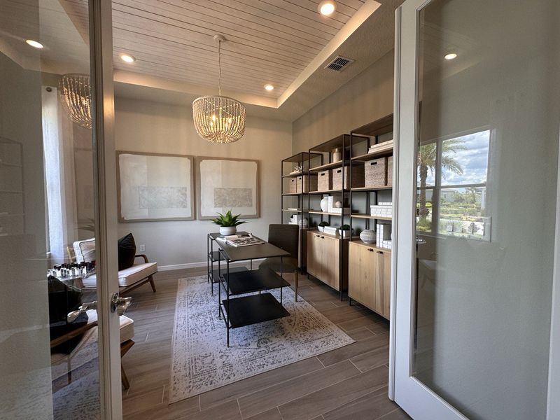 A cozy study featuring a wood-paneled ceiling, chic lighting, and modern shelving, creating a perfect workspace.