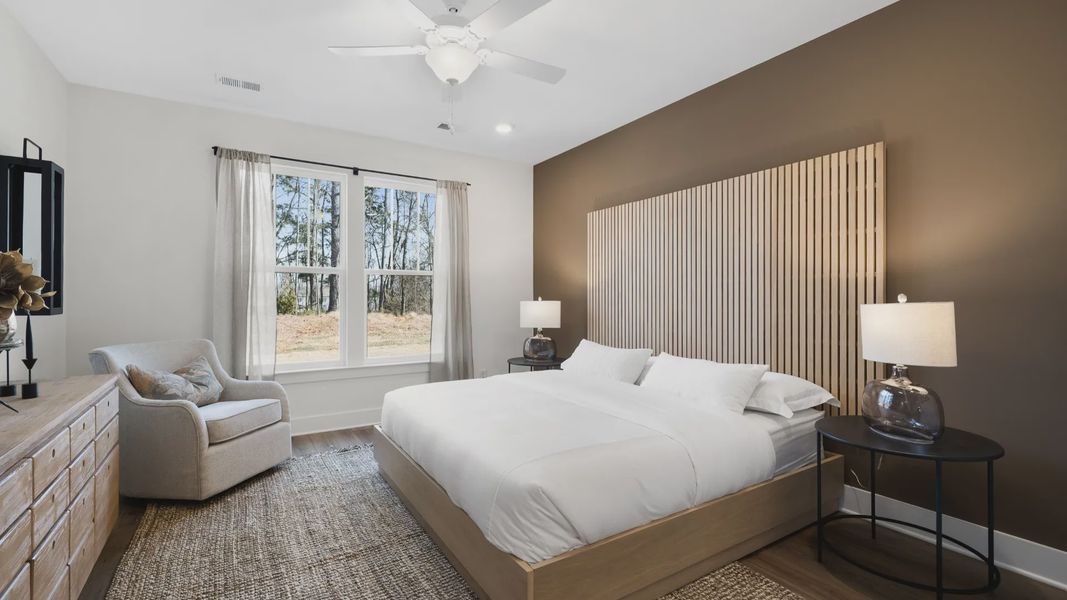 Primary suite featuring a large natural wood slat headboard and dark accent wall at Village at Midway in Anderson, SC Primary suite featuring a large natural wood slat headboard and dark accent wall at Village at Midway in Anderson, SC