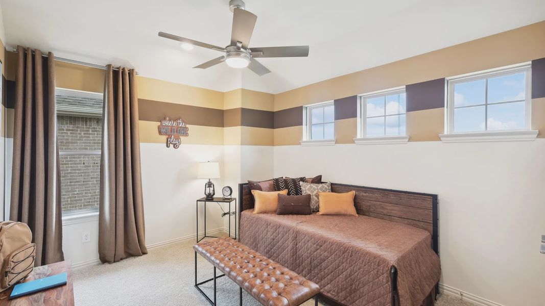 Experience luxury with striped accent walls and sleek ceiling fan in The Oaks community.