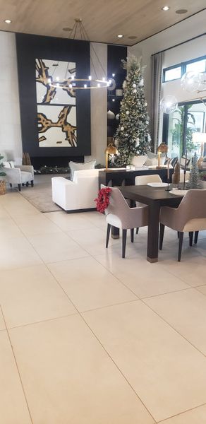 A chic living and dining area with modern art, elegant seating, and a festive Christmas tree.