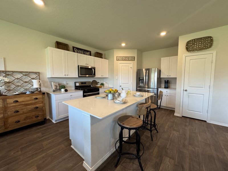 A modern kitchen featuring a spacious island, chic barstools, stainless steel appliances, and warm wood accents.