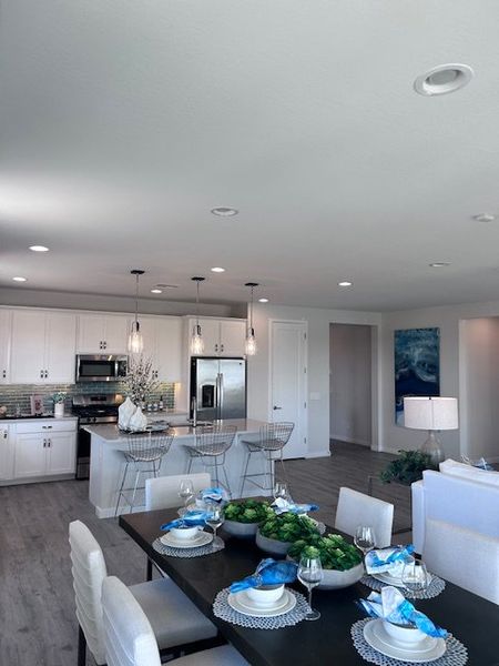 A modern open-concept kitchen and dining area with sleek finishes, pendant lighting, and contemporary decor.