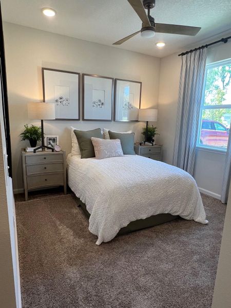 A cozy bedroom featuring a plush carpet, neutral décor, and elegant lighting, creating a serene retreat.