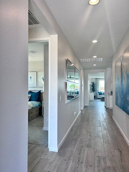 A modern hallway with sleek wood flooring, neutral walls, and contemporary artwork, leading to an airy living space. A modern hallway with sleek wood flooring, neutral walls, and contemporary artwork, leading to an airy living space.
