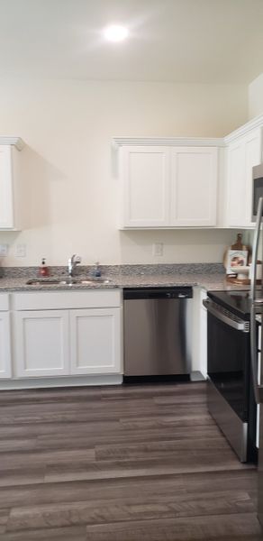 A modern kitchen with sleek white cabinets, granite countertops, and stainless steel appliances. A modern kitchen with sleek white cabinets, granite countertops, and stainless steel appliances.