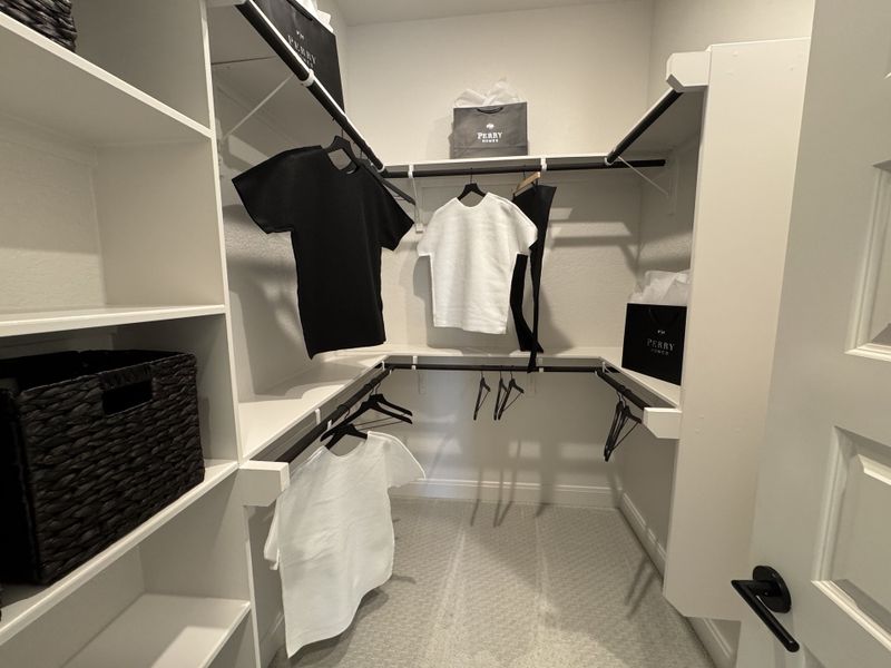 A spacious walk-in closet featuring white shelving, elegant rods, and sleek storage baskets, offering ample organization. A spacious walk-in closet featuring white shelving, elegant rods, and sleek storage baskets, offering ample organization.