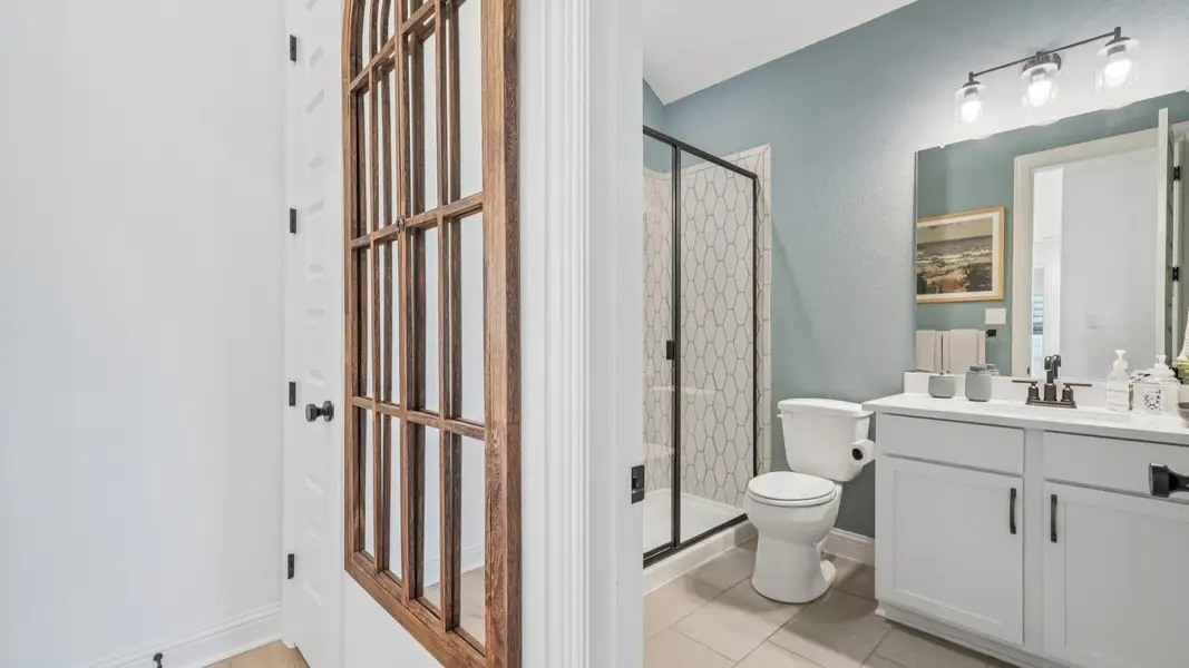 Secondary bathroom with ceramic tile shower, black framed glass door, and single vanity Secondary bathroom with ceramic tile shower, black framed glass door, and single vanity