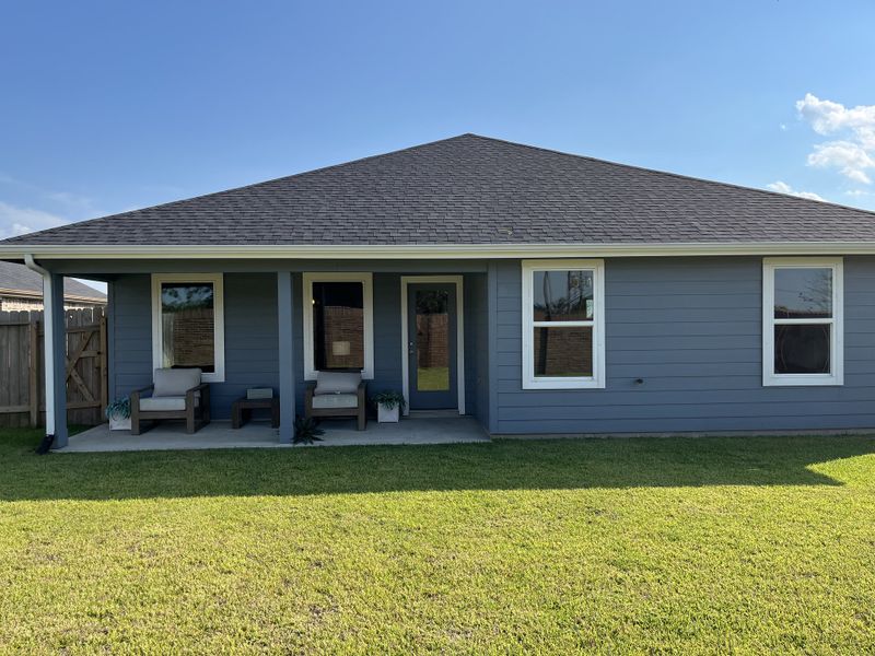 Modern gray home with inviting porch in the Watermark community by D.R. Horton, featuring a well-maintained yard (Alvin, TX).