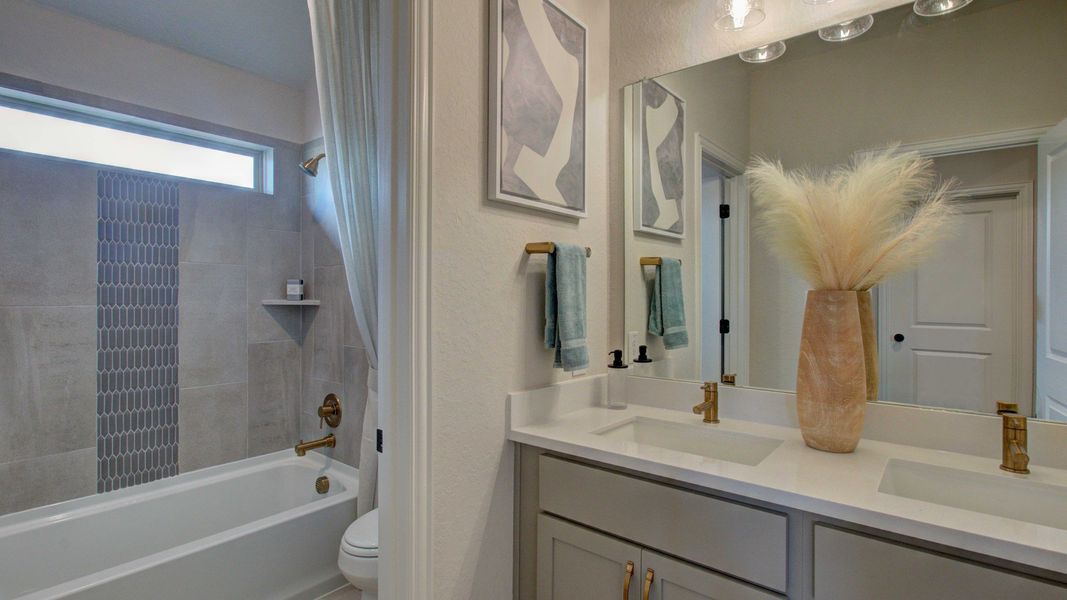 Elegant dual sinks, modern brass fixtures, and chic tile design elevate this Enclave at Meyer Ranch bathroom.