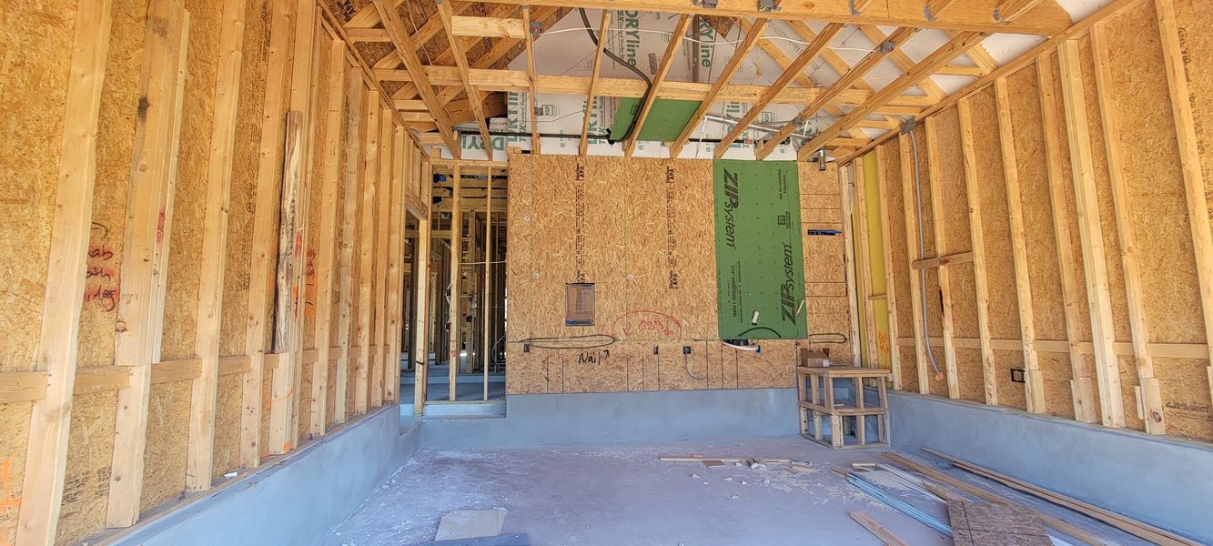 Under-construction interior with exposed framing, insulation, and wiring, ready for further development and finishing.
