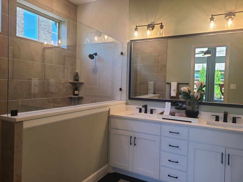 Modern bathroom featuring dual sinks, sleek black fixtures, and a spacious glass shower accented with elegant tiles.