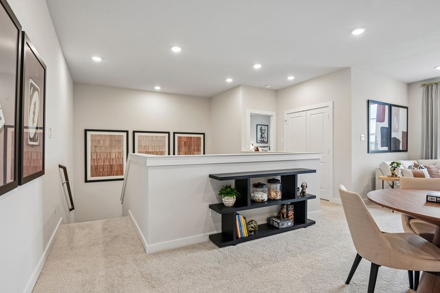 A room with a large white counter and a black table with chairs.