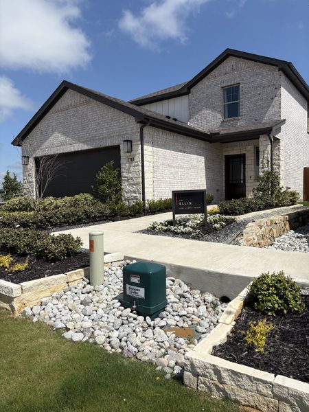 A modern brick home with a sleek facade and manicured yard in Churchill by HistoryMaker Homes (Anna, TX).