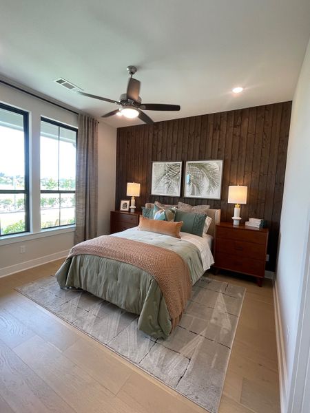 A cozy bedroom featuring a wooden accent wall, stylish bedding, and ample natural light from large windows. A cozy bedroom featuring a wooden accent wall, stylish bedding, and ample natural light from large windows.