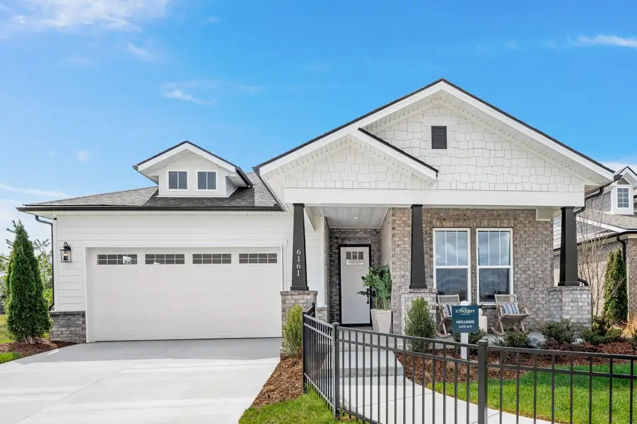Single-story craftsman home with brick and shingle exterior, covered front porch, and two-car garage