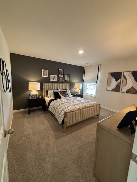 A cozy bedroom with a dark accent wall, stylish decor, and plush carpeting for a modern and inviting atmosphere.