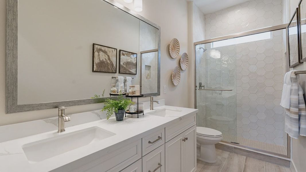 This Windrose bathroom features elegant hexagonal shower tiles, dual sinks, and a spacious vanity.