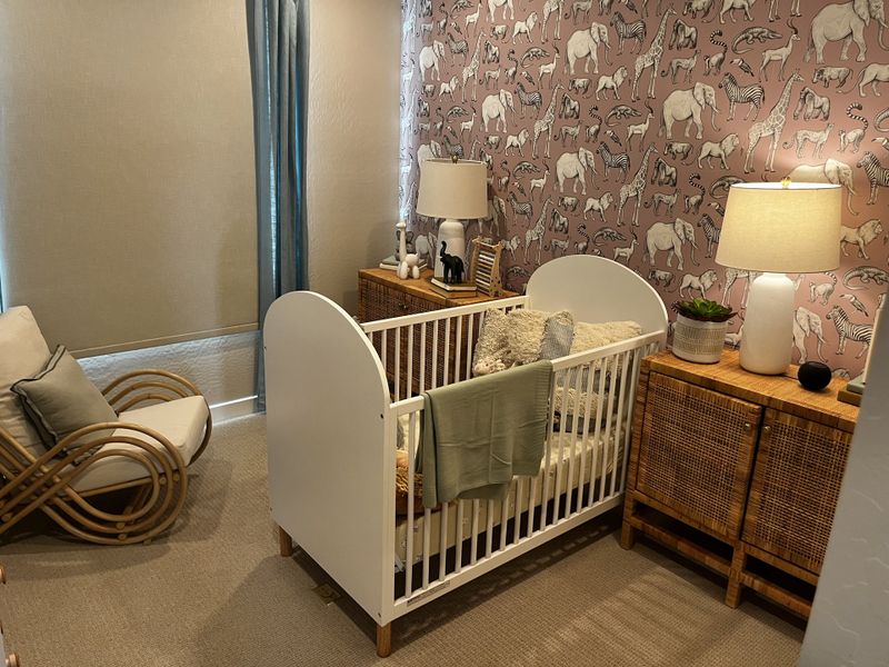 Adorable nursery with animal-themed wallpaper, a white crib, and wicker furniture for a warm, cozy feel.