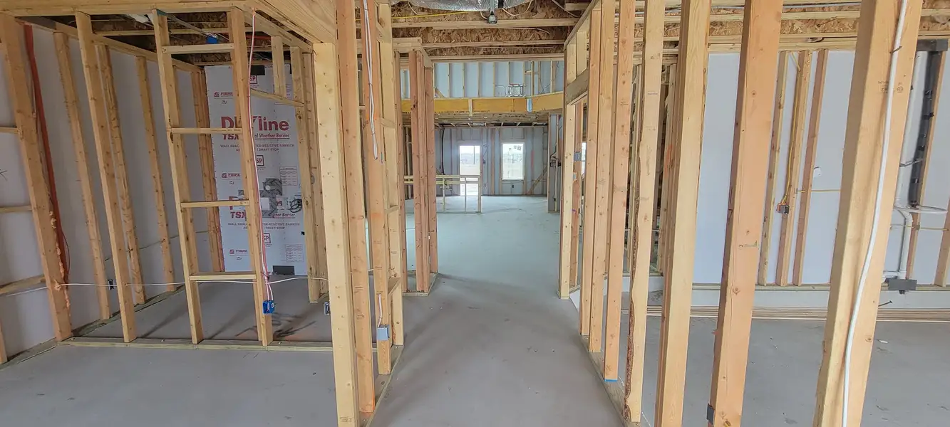 A room under construction featuring wooden framing and exposed wiring, showcasing the early stages of a building project.