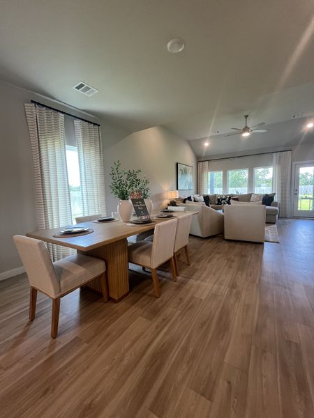 A spacious living and dining area with wood flooring, neutral tones, and large windows for natural light. A spacious living and dining area with wood flooring, neutral tones, and large windows for natural light.