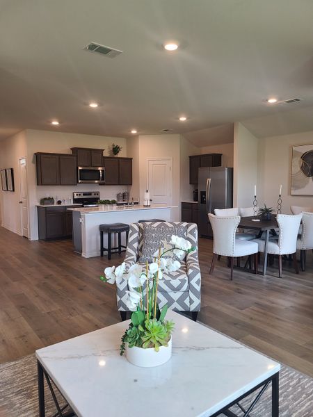 Open-concept living space with modern kitchen, wood floors, and elegant dining area under soft lighting. Open-concept living space with modern kitchen, wood floors, and elegant dining area under soft lighting.