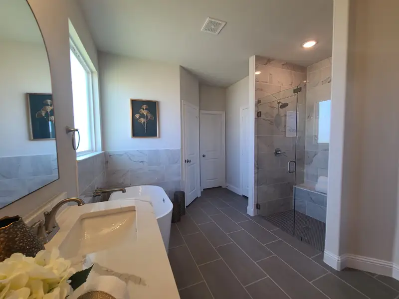 A luxurious bathroom featuring a freestanding tub, sleek vanity, and glass-enclosed shower with elegant tile accents.