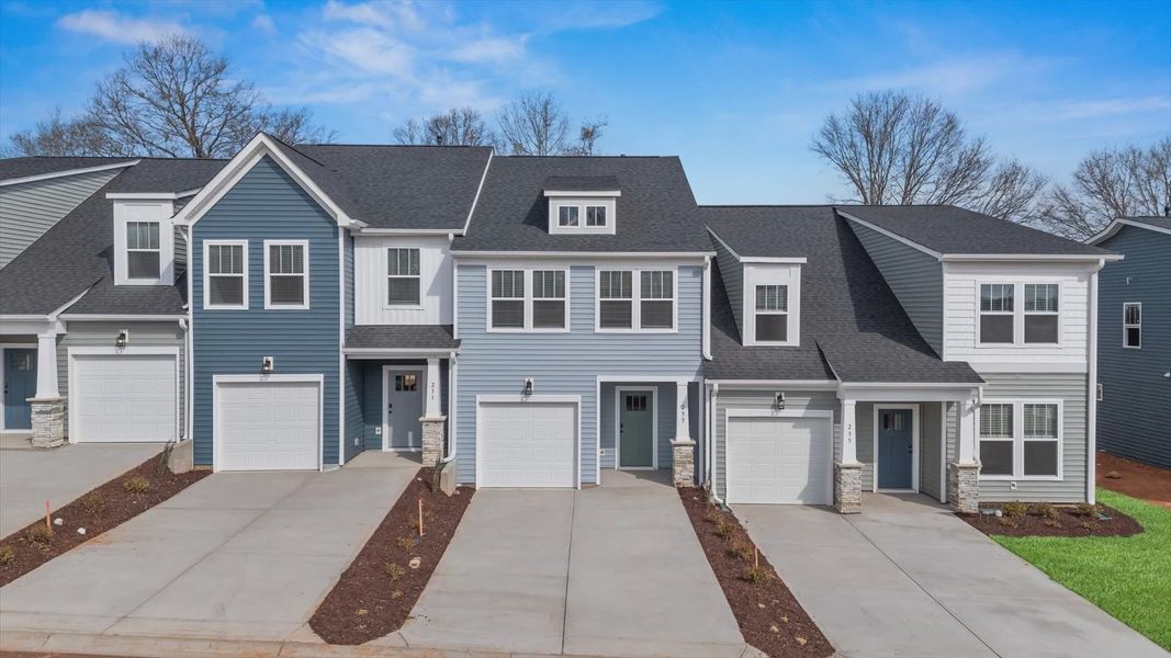 Townhome with light blue exterior siding, seafoam green door, large windows, and two car driveway with one car garage Townhome with light blue exterior siding, seafoam green door, large windows, and two car driveway with one car garage