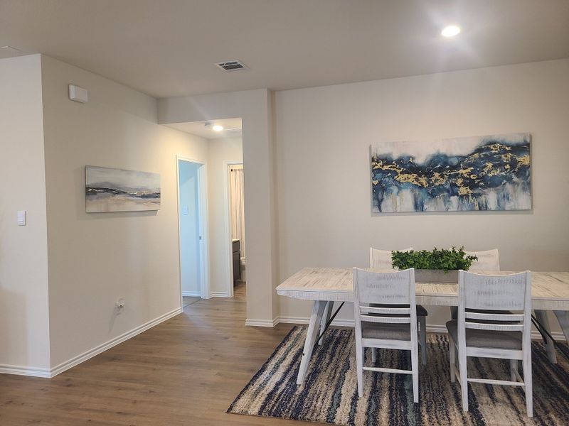 A modern dining area with a whitewashed table, abstract art, and wood flooring, creating a cozy and stylish setting.