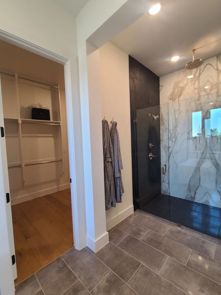 Luxurious bathroom with a marble shower, dark accents, and a spacious walk-in closet. Luxurious bathroom with a marble shower, dark accents, and a spacious walk-in closet.