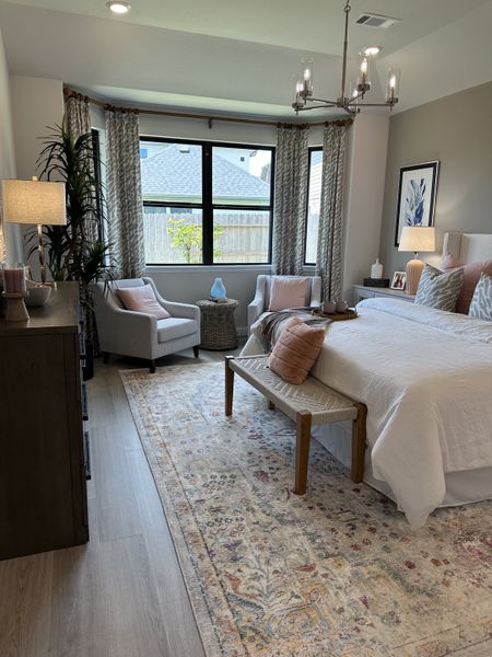 A serene bedroom with a cozy seating area, elegant chandelier, and soft neutral tones creating a welcoming retreat. A serene bedroom with a cozy seating area, elegant chandelier, and soft neutral tones creating a welcoming retreat.