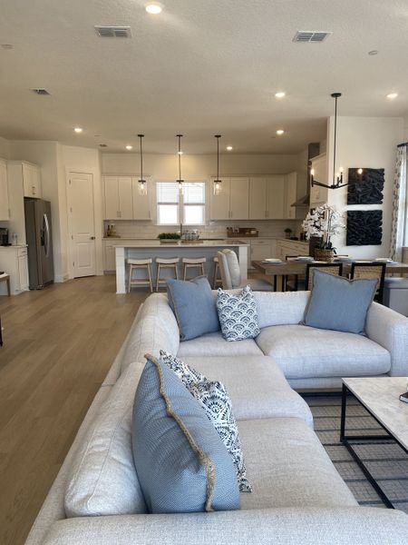 An inviting open-plan living area with a cozy sectional, modern kitchen, and stylish pendant lighting. An inviting open-plan living area with a cozy sectional, modern kitchen, and stylish pendant lighting.