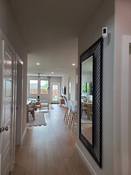 A modern hallway with wood flooring, chic decor, and a spacious open-concept living area leading to a bright backyard view.