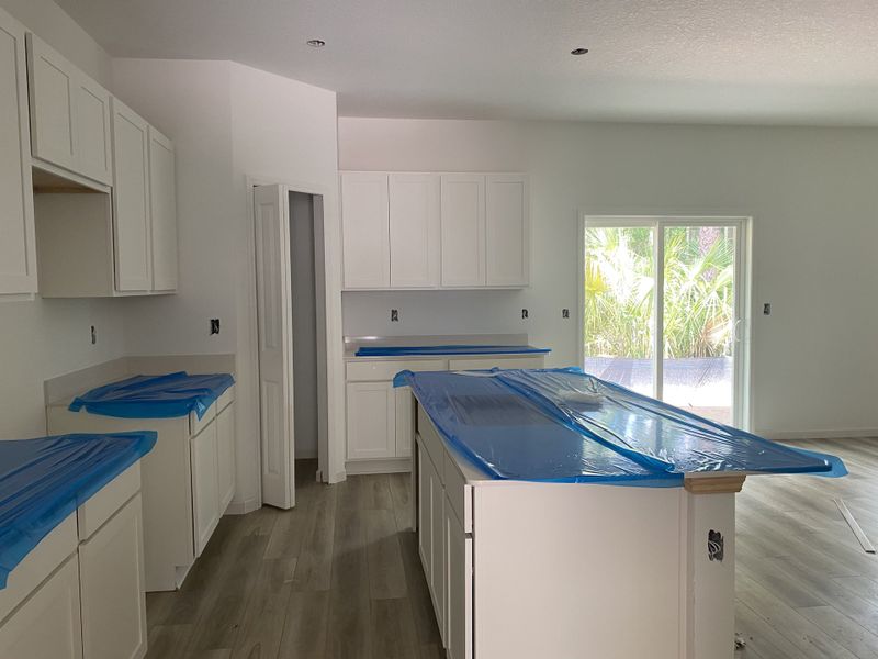 A modern kitchen with bright white cabinets, sleek countertops, and a large island, accentuated by natural light.