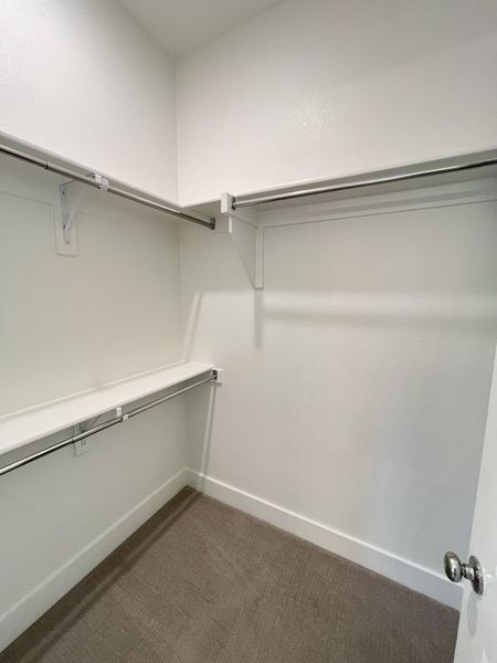A spacious walk-in closet with stylish shelving and ample hanging space, offering organized storage solutions. A spacious walk-in closet with stylish shelving and ample hanging space, offering organized storage solutions.