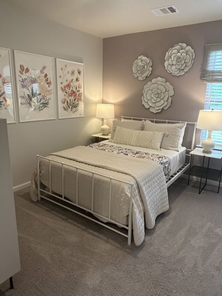 A cozy bedroom featuring floral wall art, a soft carpet, and elegant lighting, creating a serene and inviting atmosphere. A cozy bedroom featuring floral wall art, a soft carpet, and elegant lighting, creating a serene and inviting atmosphere.