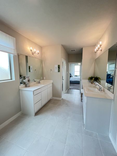 A spacious bathroom featuring dual vanities, elegant lighting, and a serene neutral palette.