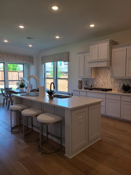 A modern kitchen with sleek white cabinets, a spacious island, and warm wood floors.